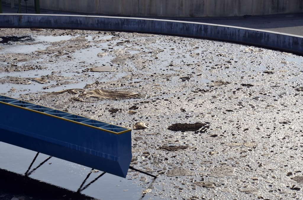 The Powerful Role Of Minuscule Microbes In Effective Wastewater Treatment 1 Wastewater treatment tank with minuscule microbes on the surface, aiding in sludge breakdown.