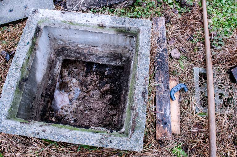 An open, square concrete septic tank showing waste inside, symbolizing septic systems potentially impacted by COVID-19.