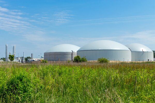 Sustainable Biogas Production From Wastewater Treatment Plants 1 Sustainable biogas plant with large digesters in a grassy field under a clear blue sky.