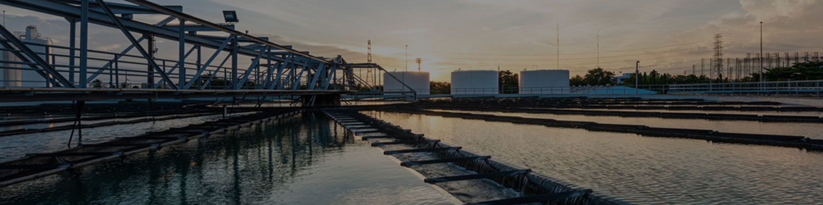 Bacterial culture for wastewater treatment in aerobic facility with channels and bridge at sunset.