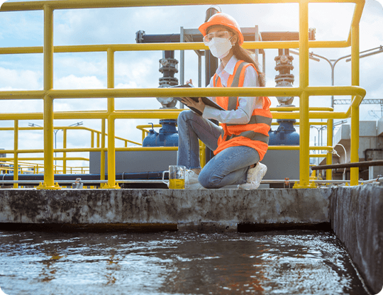Female Engineer Wearing Safety Gear Conducting Water Quality Tests at a Wastewater Treatment Facility