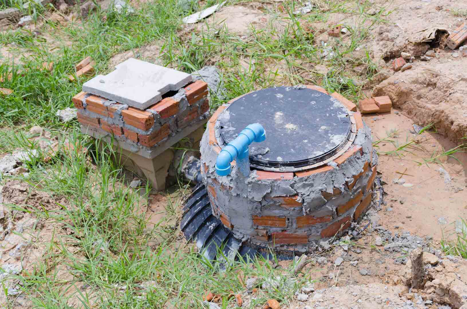 Newly installed septic tank access points with bricks and pipes, indicating residential wastewater systems and potential FOG issues.